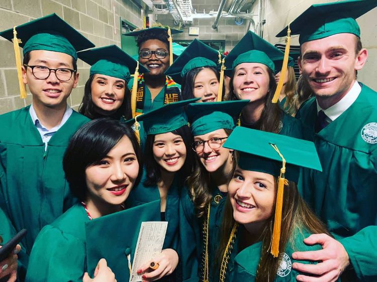 Students pose for photo at graduation in caps and gowns.