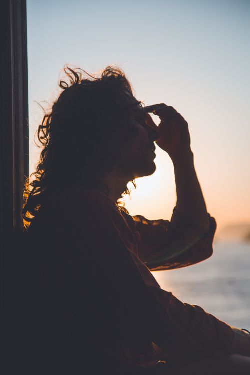 A person sitting in a window at dusk.