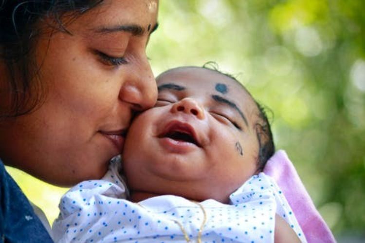 A mother holding a smiling infant.