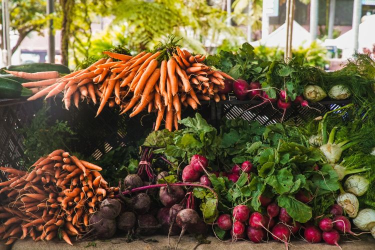 Fresh produce stacked high at a farmers market stall.