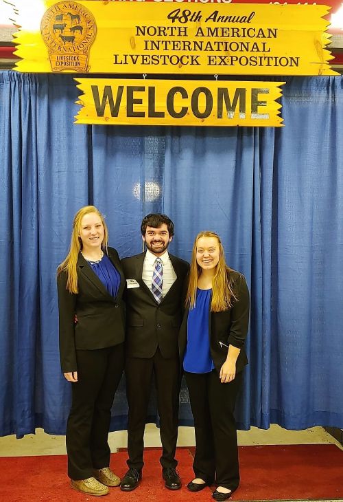 Three young adults posing for a photo together at the North American International Livestock Exposition.