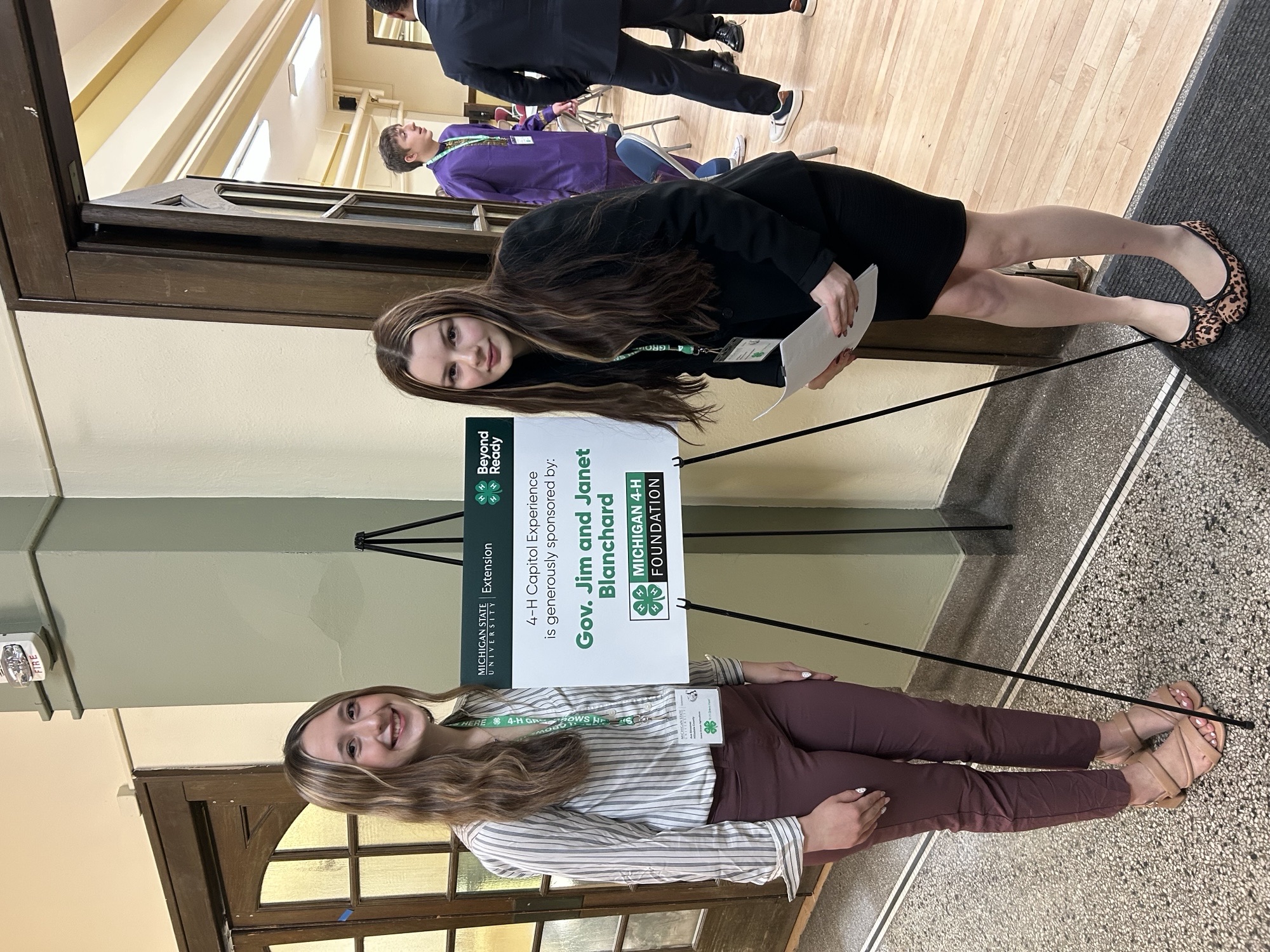 Two youth next to a sign that says "4-H Capitol Experience is generously sponsored by Gov. Jim and Janet Blanchard."