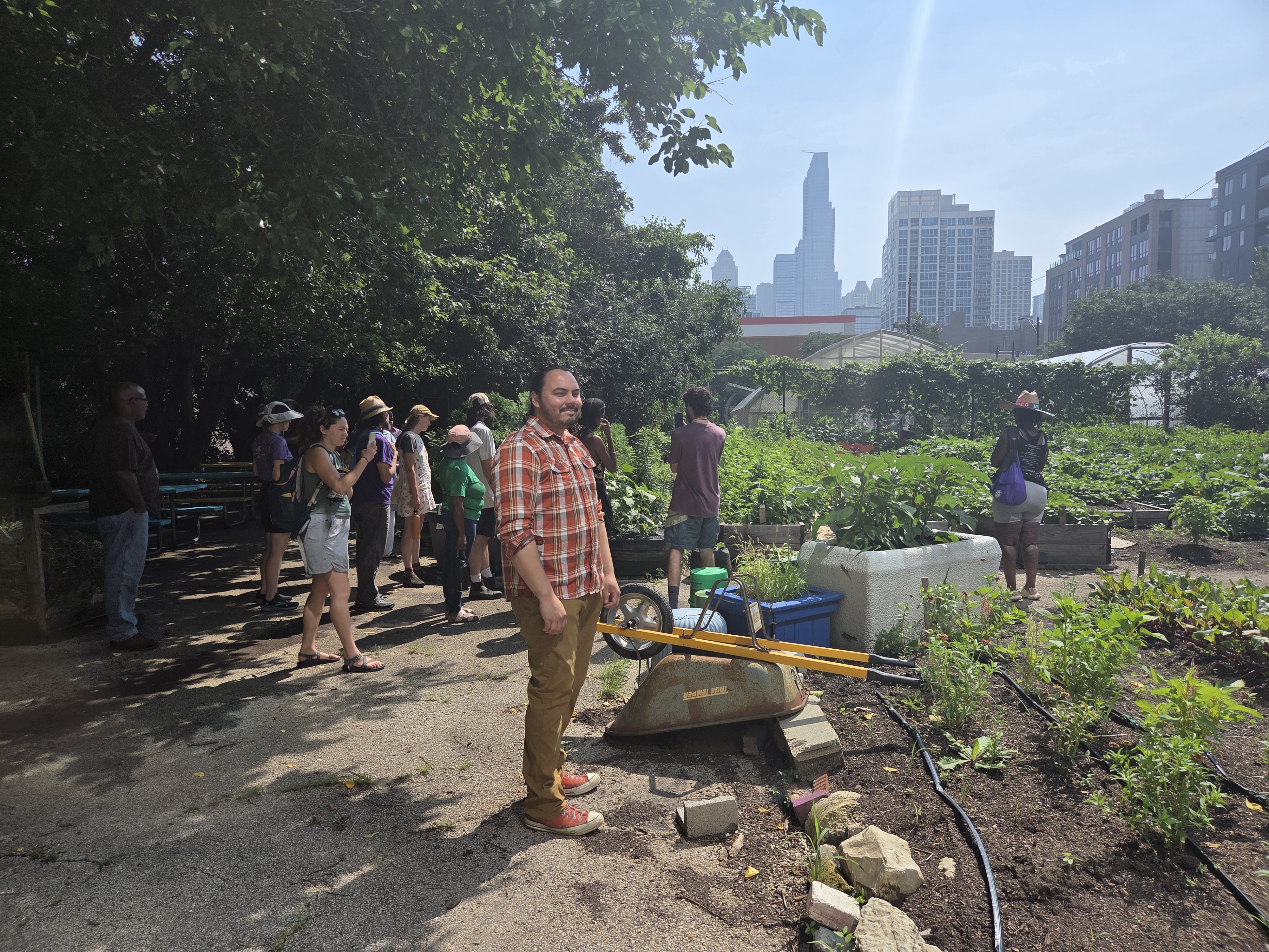 about 20 farmers looking at a vibrant garden with tall Chicago buildings in the background