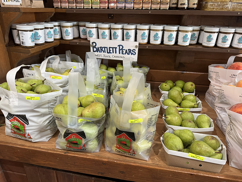 Bags of pears for sale on a wooden shelf.