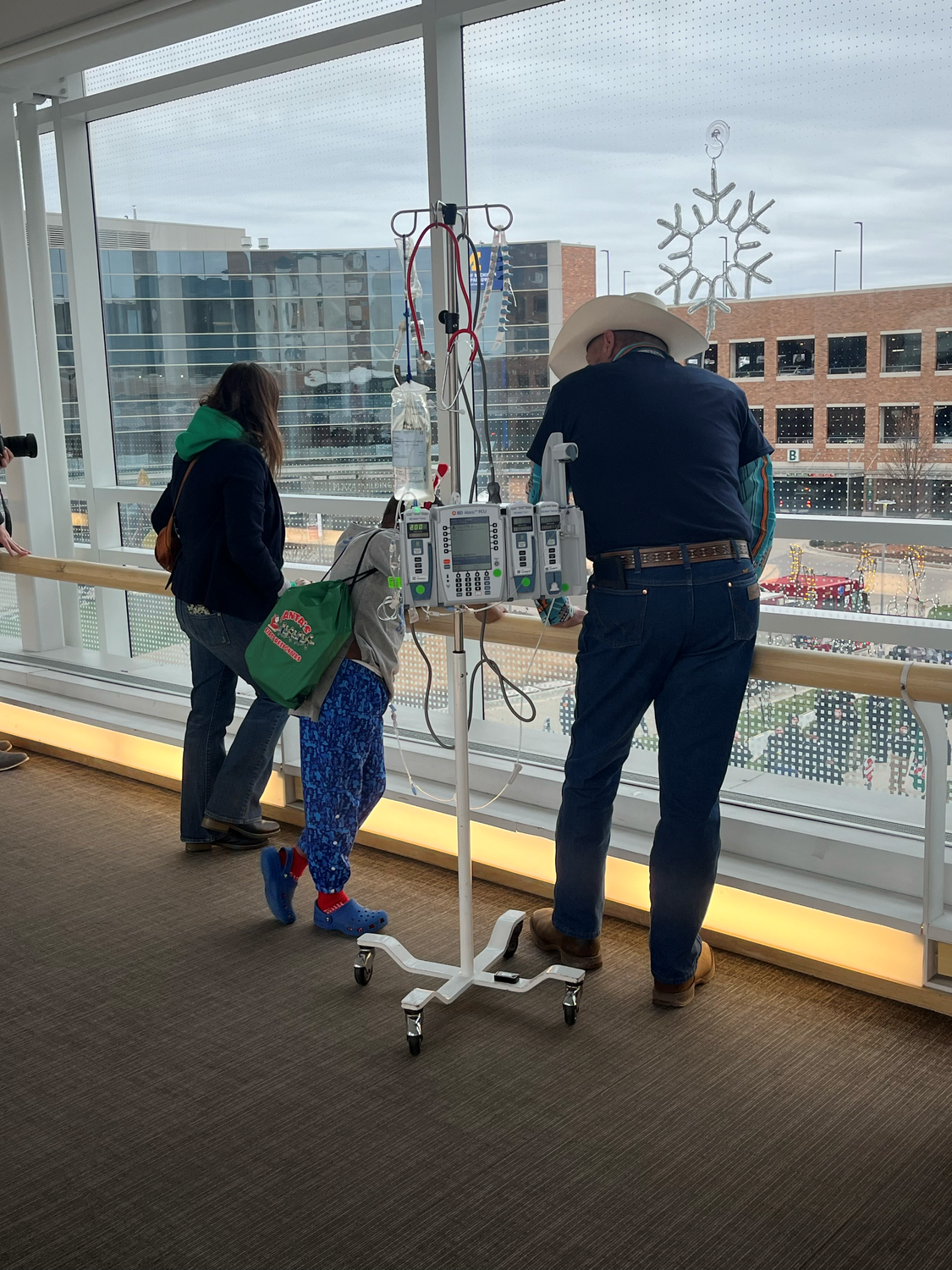 Image of Gayelord Mankowski looking out of the window of Sparrow hospital next to an unidentified pedatric cancer patient. 