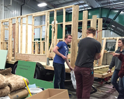 Walls going up with Tom Lyons leading the front porch installation on Sparty's Cabin.